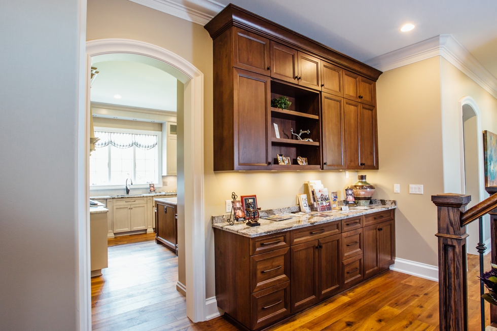 Taupe Custom Kitchen with Wood Island & Pantry - Home center built-in - Family owned western new york custom cabinetry serving williamsville, amherst, clarence, and east aurora. #benjaminmoore #plymouthrock #recessedcabinetry #undercabinetlighting #jenn-air #woodisland #cambriacountertops #breakfastbanquet #homeshow