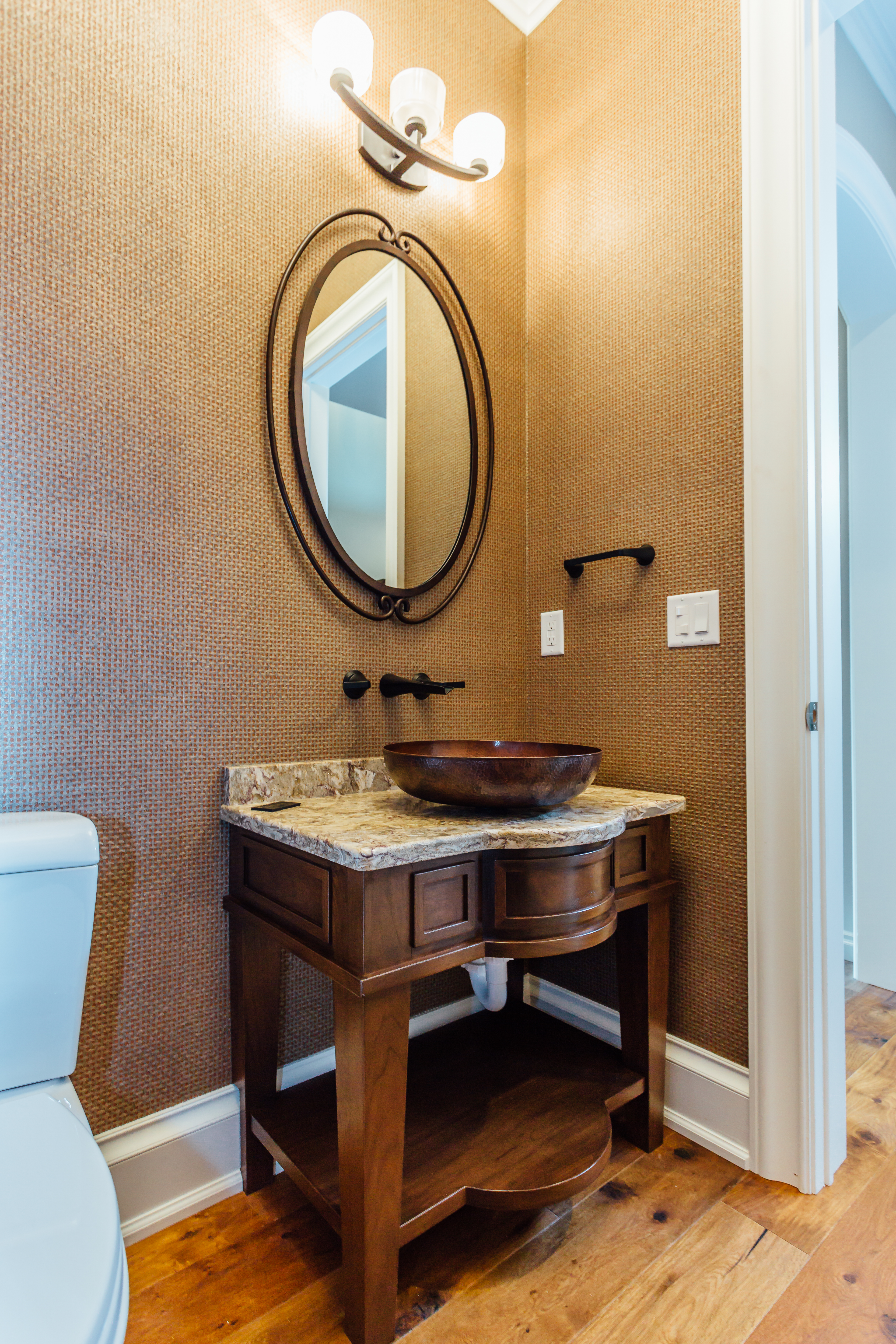 Custom made powder room vanity cabinetry in walnut with copper bowl sink basin and wall mounted faucet in black finish & textured wallpaper