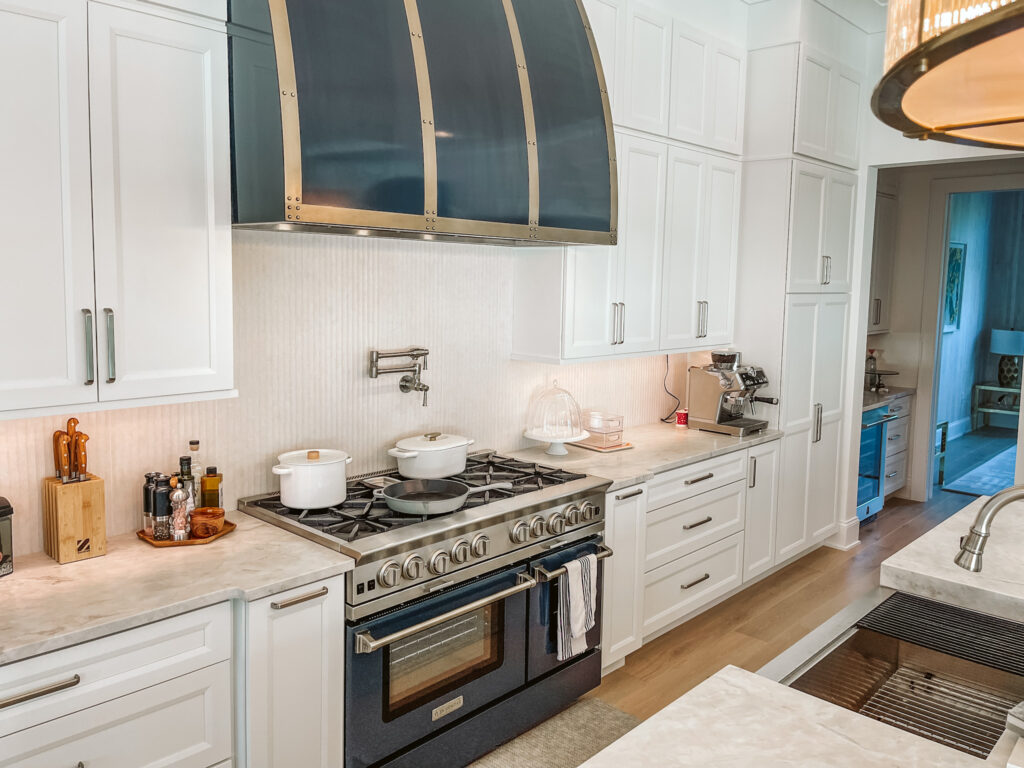 White painted kitchen with custom metal hood with brass accents